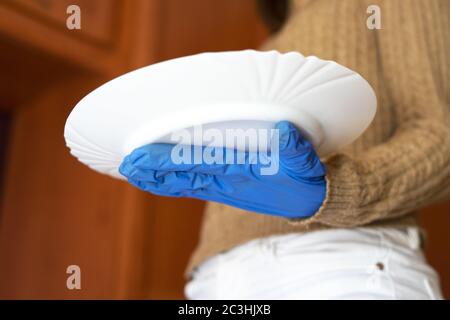 Un primo piano di una mano femminile con un guanto medico che tiene un piatto bianco Foto Stock
