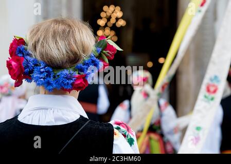 Donna con corona di fiori, vestita in un elegante costume popolare nazionale di Lowicz. Tradizionale abito popolare colorato. Vista posteriore della fascia floreale Foto Stock