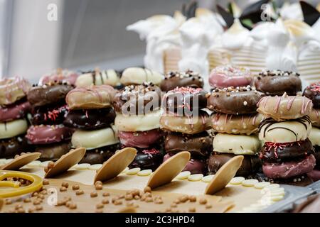 montagna di piccole ciambelle decorate in modo diverso in una vetrina gelato Foto Stock