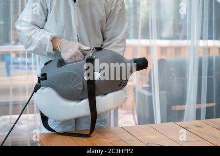 "Uomo tecnico professionale nella prevenzione spray spray spray soluzione sterilizzante da spray elettrici nella sala di vetro interna." Foto Stock