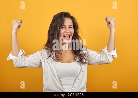 Armi su celebrare i pugni di successo nell'esultazione. Giovane donna attraente, vestita Foto Stock