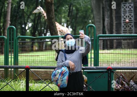 I visitatori indossano maschere al Ragunan Wildlife Park, Jakarta, sabato 20 giugno 2020. Il Ragunan Wildlife Park è stato riaperto per i visitatori nella terza settimana della fase di apertura della prima fase della transizione alle nuove restrizioni sociali normali o su larga scala (PSBB). Ma il Ragunan Wildlife Park limita il numero di visitatori a 1000 persone al giorno, con l'attuazione di rigorosi protocolli di salute. Come richiesto dalla registrazione online, i bambini sotto i 9 anni, le donne incinte e gli anziani sopra i 60 anni non sono autorizzati ad entrare, i visitatori sono anche tenuti a utilizzare e portare la propria maschera e sanitiz mani Foto Stock