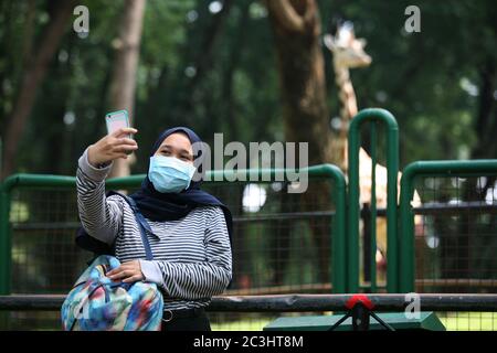 I visitatori indossano maschere al Ragunan Wildlife Park, Jakarta, sabato 20 giugno 2020. Il Ragunan Wildlife Park è stato riaperto per i visitatori nella terza settimana della fase di apertura della prima fase della transizione alle nuove restrizioni sociali normali o su larga scala (PSBB). Ma il Ragunan Wildlife Park limita il numero di visitatori a 1000 persone al giorno, con l'attuazione di rigorosi protocolli di salute. Come richiesto dalla registrazione online, i bambini sotto i 9 anni, le donne incinte e gli anziani sopra i 60 anni non sono autorizzati ad entrare, i visitatori sono anche tenuti a utilizzare e portare la propria maschera e sanitiz mani Foto Stock