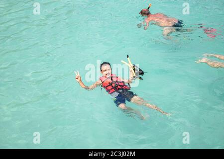 Giovane uomo che fa snorkeling in acque pulite sulla barriera corallina. Un uomo indossa una giacca Life. Foto Stock