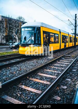 Immagine verticale di un treno giallo in movimento sul piattaforma ferroviaria esterna Foto Stock