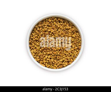 Semi di fenugreek in una ciotola di legno isolata su bianco. Semi di fenugreek isolati su sfondo bianco. Vista dall'alto. Fenugreek con spazio di copia per il testo. Foto Stock