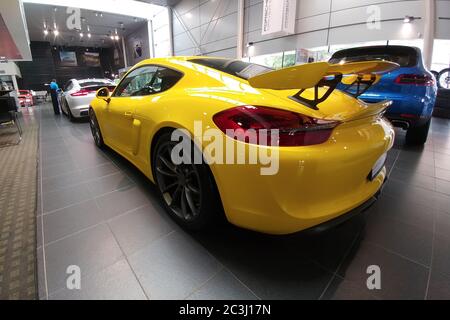 Russia, Mosca - 04 maggio 2019: Porsche Cayman GT4 gialla e Macan blu. Auto da corsa nello showroom del concessionario. Vista posteriore destra Foto Stock