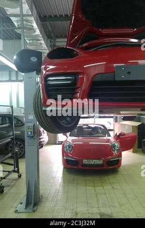 Mosca. Febbraio 2019. Porsche Pammer rossa senza fari su un ascensore su una Porsche 911 rossa. Riparare nel centro di assistenza. Diagnosi e sostituzione delle ruote Foto Stock