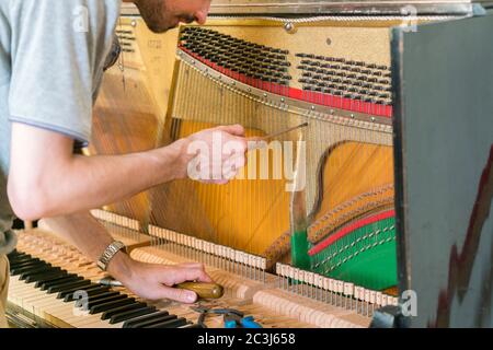 Processo di sintonizzazione del pianoforte. Primo piano della mano e strumenti di sintonizzazione che lavorano al pianoforte a coda. Vista dettagliata di piano verticale durante una sintonizzazione Foto Stock