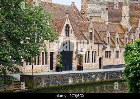 scena dei canali, edifici in mattoni, tetti ripidi in tegole, camini, grandi porte doppie nere, acqua, finestre strette, dormitori, Europa; Bruges; Belgio Foto Stock