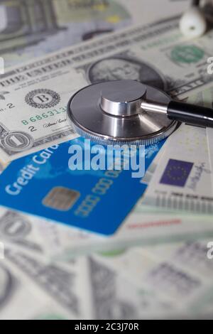 Tiro verticale ad angolo alto di uno stetoscopio su qualche dollaro bollette e una carta di credito Foto Stock