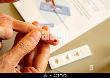 COVID-19 home Antibody test research kit. Una goccia di sangue dopo il dito è punzognata con la lancetta. Il kit include bastoncino di analisi COVID-19, lancette, liquido tampone, pipetta, salvietta imbevuta di alcool. Test di reazione per IgG positive, IgM risultati o test negativi per anticorpi. Foto Stock