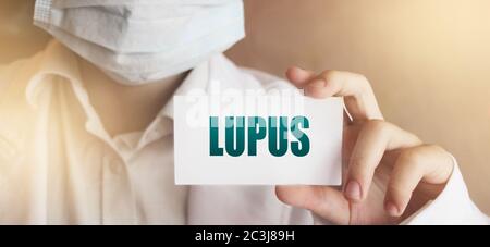 La mano del medico mostra la carta con la parola lupus. Concetto medico Foto Stock