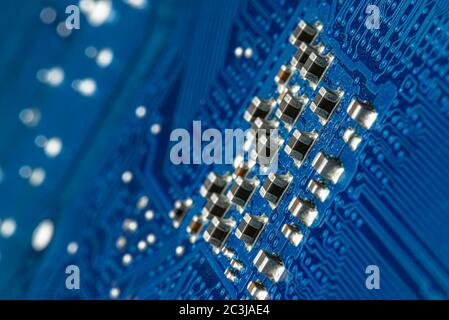 Macro foto dei percorsi elettrici sulla scheda a circuito stampato blu, resistori visibili. Foto Stock