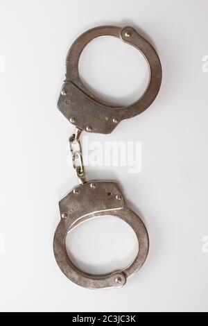 Ripresa verticale ad alto angolo di manette metalliche isolate su a. superficie bianca Foto Stock