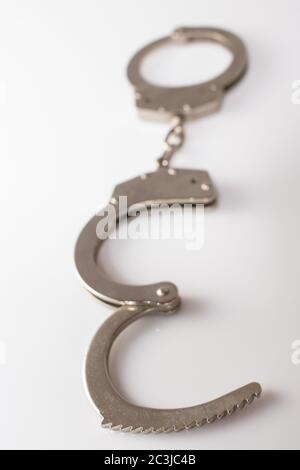 Ripresa verticale ad alto angolo di manette metalliche isolate su a. superficie bianca Foto Stock