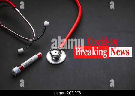 COVID-19 BREAKING NEWS text with stetoscope and Blood sample vacuum tube on black background. Concetto Di Covid O Coronavirus Foto Stock