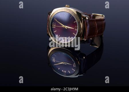 Orologio uomo con bracciale in pelle su sfondo nero lucido. Mettere a fuoco su 9 un numero di orologio. Foto Stock