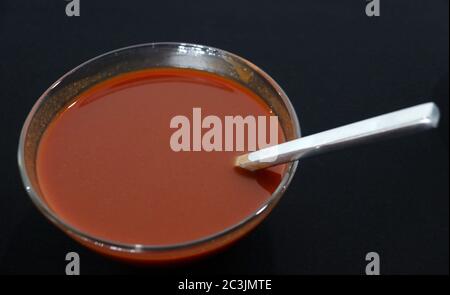 Salsa calda in recipiente di vetro con mestolo su fondo nero Foto Stock