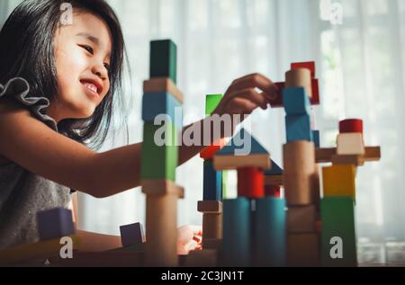 Happy bambina che gioca a costruire torre costruttore di gioco da blocchi di legno multicolore. Apprendimento e sviluppo di background concetto. Foto Stock