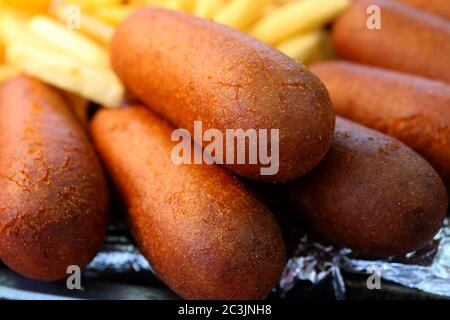 Cani da mais con patatine fritte alla fiera di strada Foto Stock