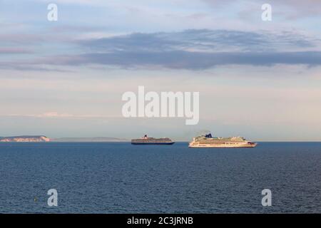 Bournemouth, Dorset UK. 20 giugno 2020. Le navi da crociera P&o Arcadia e Aurora ormeggiate a Poole Bay, Bournemouth, sulla costa meridionale, sono state unite da P&o Ventura e dalla Queen Victoria di Cunard come spazio insufficiente a Southampton; Non stanno navigando a causa della pandemia di Coronavirus che chiude il settore crocierario costringendo le aziende a mettere le loro navi. L'aurora si illumina nella luce della sera vista dalla spiaggia con le nuvole nel cielo. Credit: Carolyn Jenkins/Alamy Live News Foto Stock