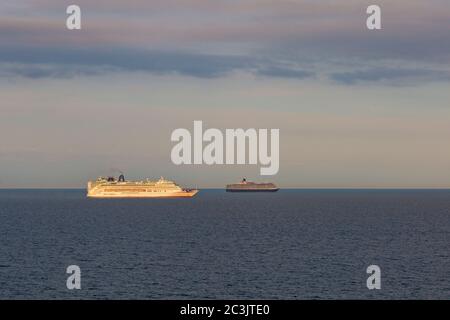 Bournemouth, Dorset UK. 20 giugno 2020. Le navi da crociera P&o Arcadia e Aurora ormeggiate a Poole Bay, Bournemouth, sulla costa meridionale, sono state unite da P&o Ventura e dalla Queen Victoria di Cunard come spazio insufficiente a Southampton; Non stanno navigando a causa della pandemia di Coronavirus che chiude il settore crocierario costringendo le aziende a mettere le loro navi. L'aurora si illumina nella luce della sera vista dalla spiaggia con le nuvole nel cielo. Credit: Carolyn Jenkins/Alamy Live News Foto Stock