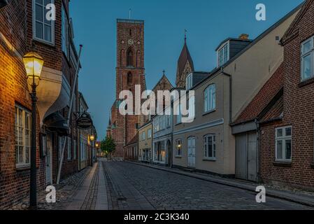 La torre della cattedrale di Ribe alla fine di una strada acciottolata nella luce soffusa della sera, Ribe, Danimarca, 29 maggio 2020 Foto Stock