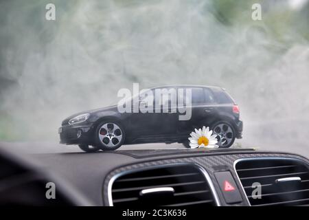 Mosca. Autunno 2018. L'auto giocattolo nera rimane nel fumo sul cruscotto della stessa auto reale. Volkswagen golf 6, logo mat vw Foto Stock
