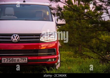 San Pietroburgo, Russia - 22 luglio 2019: Volkswagen moderno Voltivan California Ocean (Transporter) di colore rosso e bianco. È parcheggiato nella foresta all'alba lato anteriore closeup Foto Stock