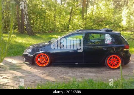 Russia, Mosca - 01 giugno 2019: Volkswagen Golf Mk6 nero sintonizzato con ruote ragtop e arancione. Regolazione della posizione sulle sospensioni pneumatiche in verde foresta. Lato sinistro Foto Stock