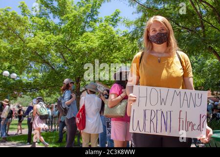 La giovane donna bianca tiene in su segno che legge 'quanti non sono stati filmati?' A una protesta Black Lives Matter a Santa Fe, New Mexico, USA Foto Stock