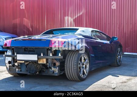 Cabriolet Super CAR. Danni al paraurti posteriore e anteriore dopo un incidente. Servizio e messa a punto. Sullo sfondo della parete di ferro Foto Stock