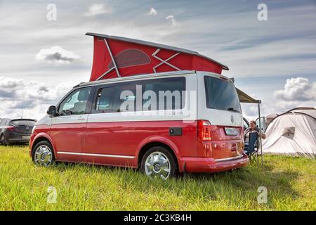 San Pietroburgo, Russia - 22 luglio 2019: Volkswagen moderno Volkswagen Multivan California Ocean (Transporter T6) di colore rosso e bianco. Parcheggiato sul campo da campeggio. Vista posteriore sinistra Foto Stock