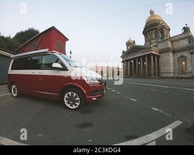 San Pietroburgo, Russia - 22 luglio 2019: Volkswagen moderno Volkswagen Multivan California Ocean (Transporter T6) di colore rosso e bianco. Parcheggiato per la notte nella strada di fronte alla cattedrale. Foto Stock