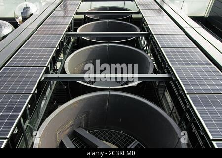 Attrezzature per esterni installate sul tetto di un grattacielo con grandi sfiati di scarico, pannelli solari e telecamere dal vivo Foto Stock