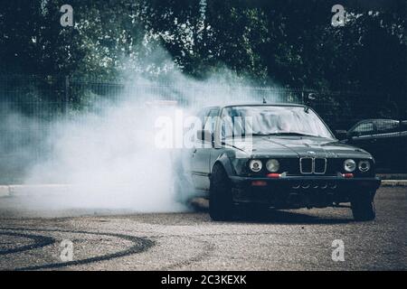 Mosca. Russia - 06 luglio 2019: Una BMW oscura si sposta nel parcheggio. Molto fumo, un burnout. Deriva illegale. Violazione di legge. Foto Stock