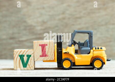 Carrello elevatore giocattolo tenere blocco di lettere per completare la parola VI (abbreviazione per investitore di valore) su sfondo di legno Foto Stock