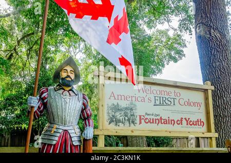 Una statua di Ponce de Leon si trova accanto a un cartello all'ingresso del Parco Archeologico della Fontana della Gioventù di Ponce de Leon a St. Augustine, Florida. Foto Stock