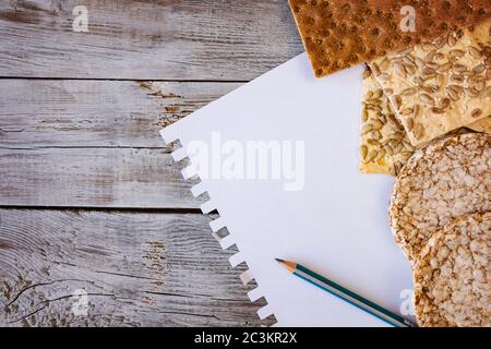 utili alimenti, croccanti, fiocchi, grano saraceno, biscotti con girasole su fondo testurizzato. Un foglio di carta a matita per scrivere il tuo testo. Foto Stock