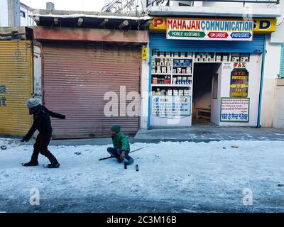 KAZA, SPITI, INDIA - 17 dicembre 2019: Due bambini nelle strade del mercato di Kaza che giocano sul ghiaccio secco Foto Stock