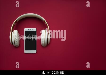 Moderno cellulare Bianco modello e cuffie su sfondo rosso gradiente con traccia Audio. Concetto musicale Foto Stock