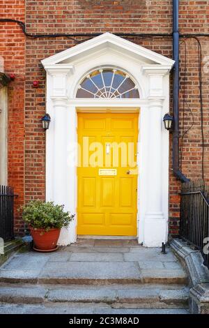 Una porta gialla a Dublino, Irlanda. Porta georgiana ad arco di fronte casa a Dublino Foto Stock