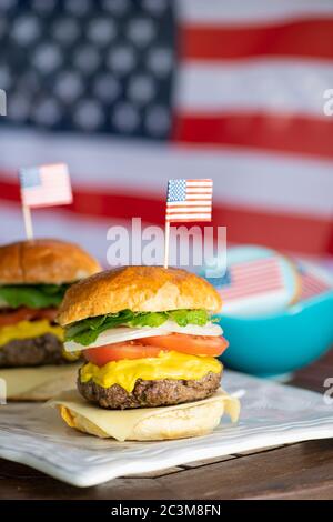 Due hamburger di manzo con bandiera americana in cima e biscotti con bandiera americana glassa per il giorno dell'indipendenza Foto Stock