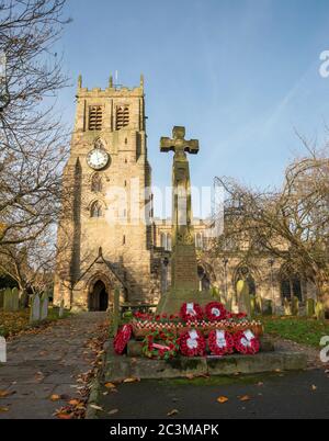 Corone di memoria di papaveri rossi intorno alla base del memoriale di guerra alla chiesa di San Gregorio, Bedale, North Yorkshire Foto Stock