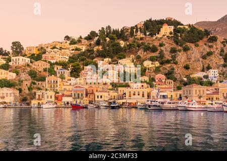 Tramonto sulle ville lato vaso di Gialos, Isola di Symi, Dodecanese, Grecia Foto Stock