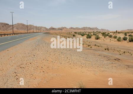 Una moderna autostrada asfaltata a due carrelli taglia le aride dune di sabbia del deserto. Foto Stock