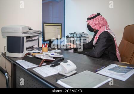 Un uomo Saudita indossa una maschera e lavora dall'ufficio il primo giorno lavorativo dopo l'apertura del divieto della pandemia di Corona Foto Stock