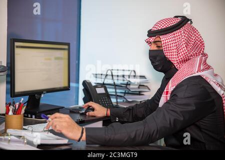 Un uomo Saudita indossa una maschera e lavora dall'ufficio il primo giorno lavorativo dopo l'apertura del divieto della pandemia di Corona Foto Stock