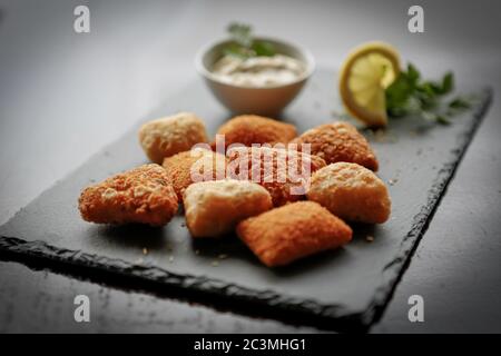 Colpo di closeup di palline fritte di formaggio di patate o crocchette su sfondo di pietra scuro. Foto Stock